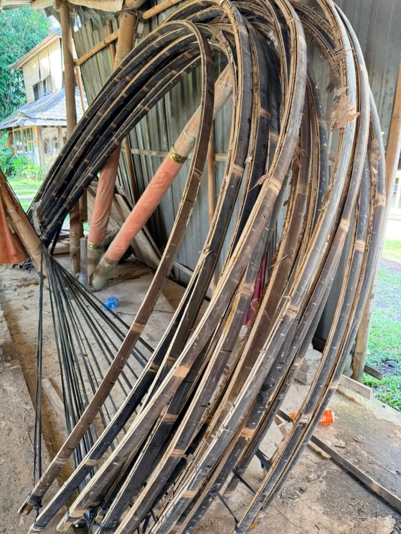 Curved split bamboo arch limbs stacked at the fabrication yard