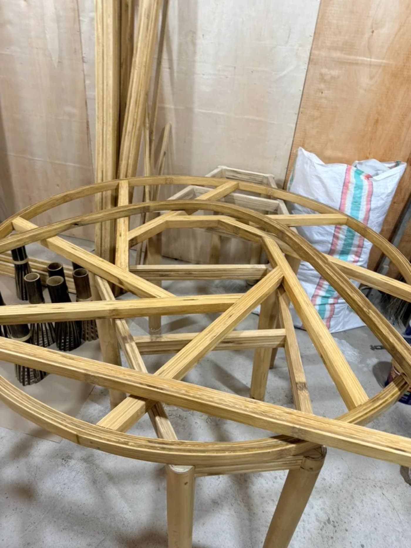 Finished laminated bamboo rings and dark woven lamp covers stacked in the workshop