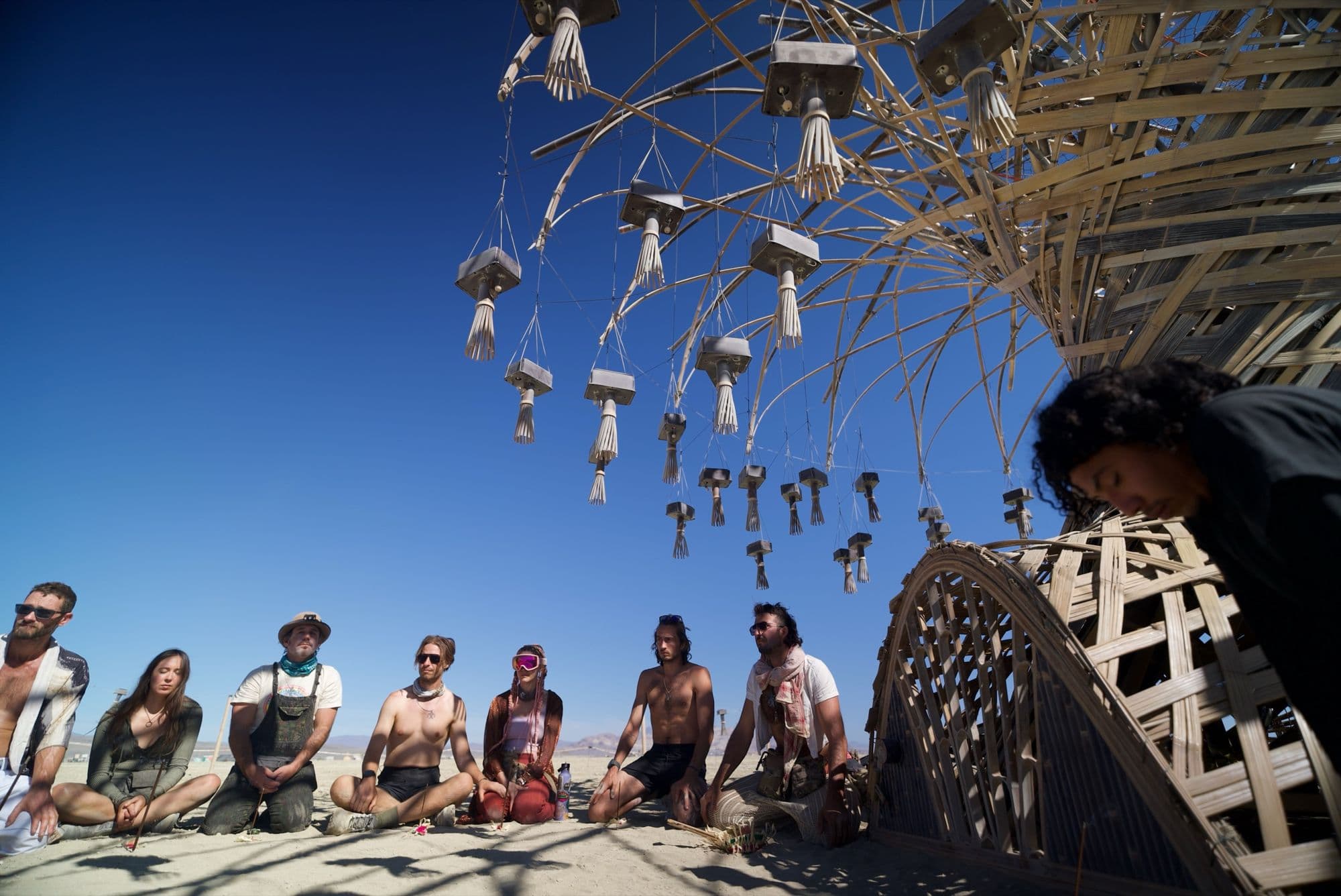 The build crew sitting in a row on the playa beneath the Resonance Tree
