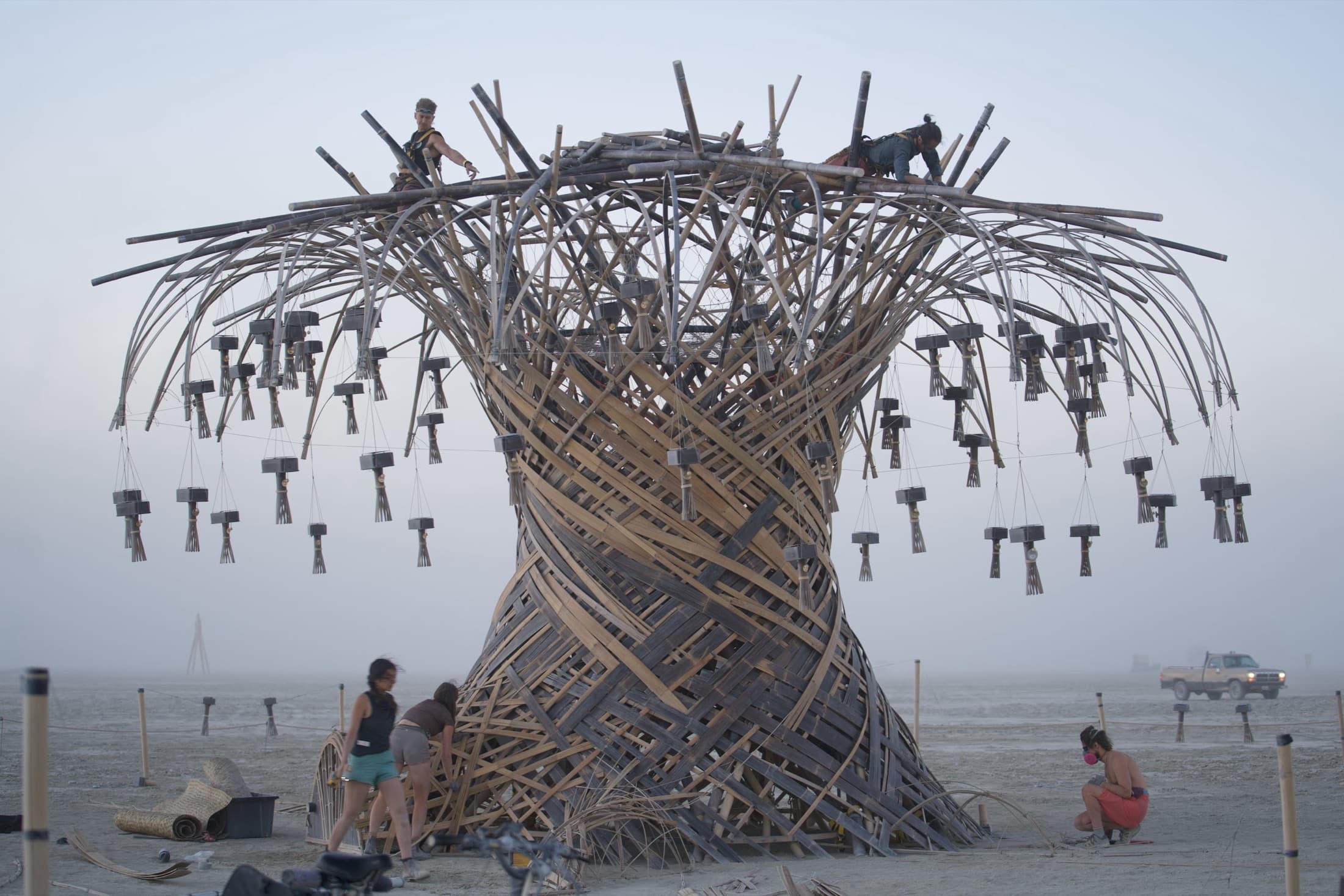 The finished Resonance Tree on open playa, chimes hung from its crown and crew on the summit