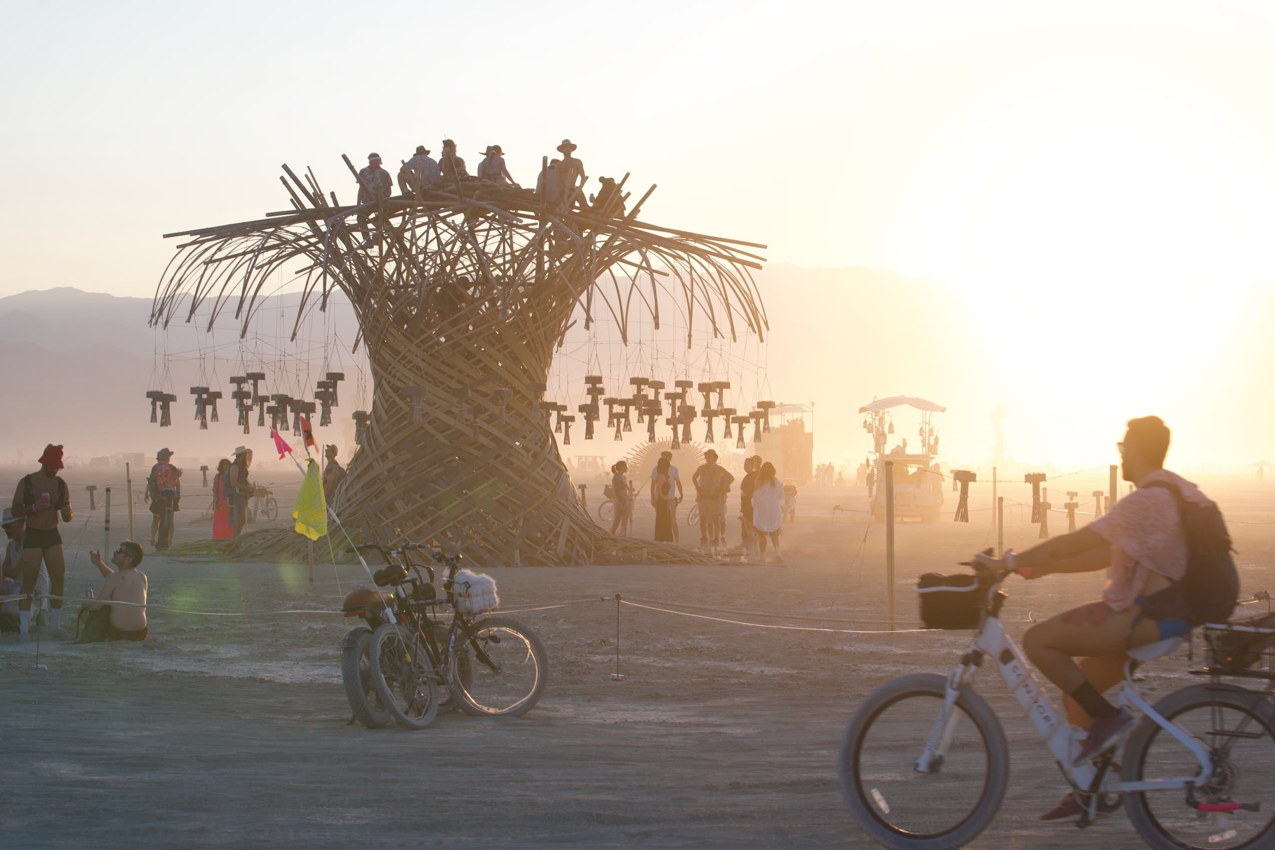 Golden hour at the Resonance Tree: the crown full of people, bikes and visitors gathered on the playa below