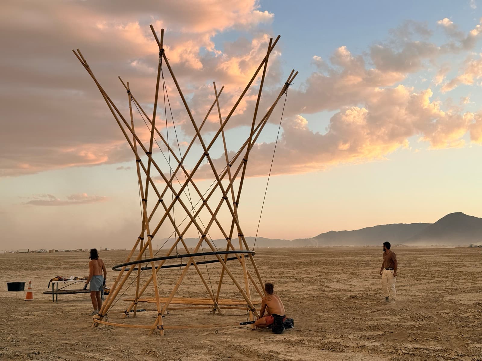 The bamboo trunk standing against sunset clouds with crew resting at its base
