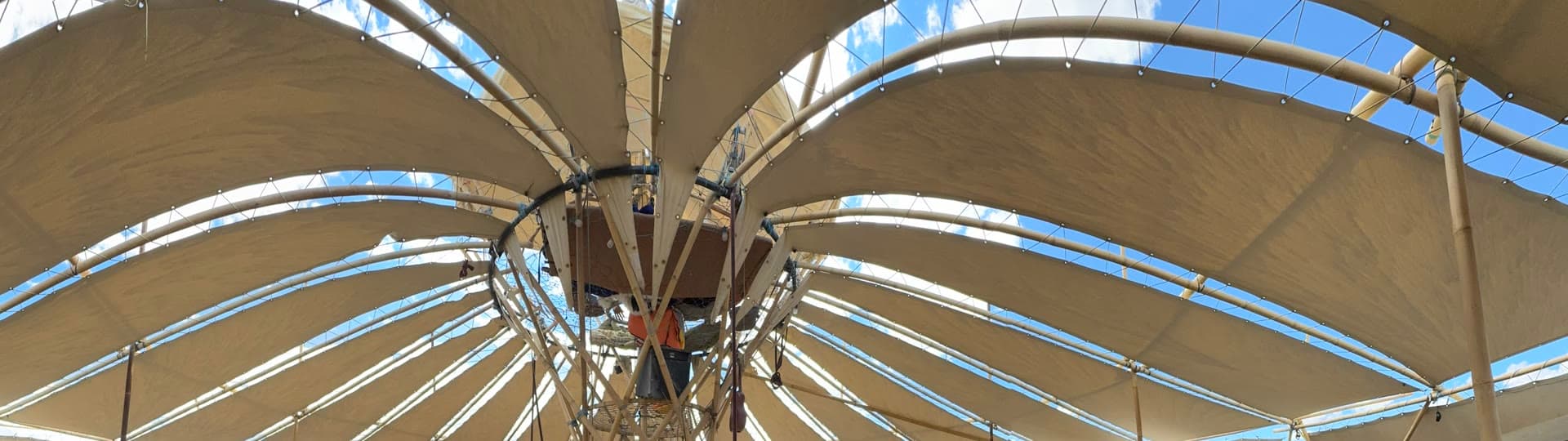 Inside the Shade Pavilion at Burning Man 2026: fabric petals radiating from a central bamboo tower against the desert sky