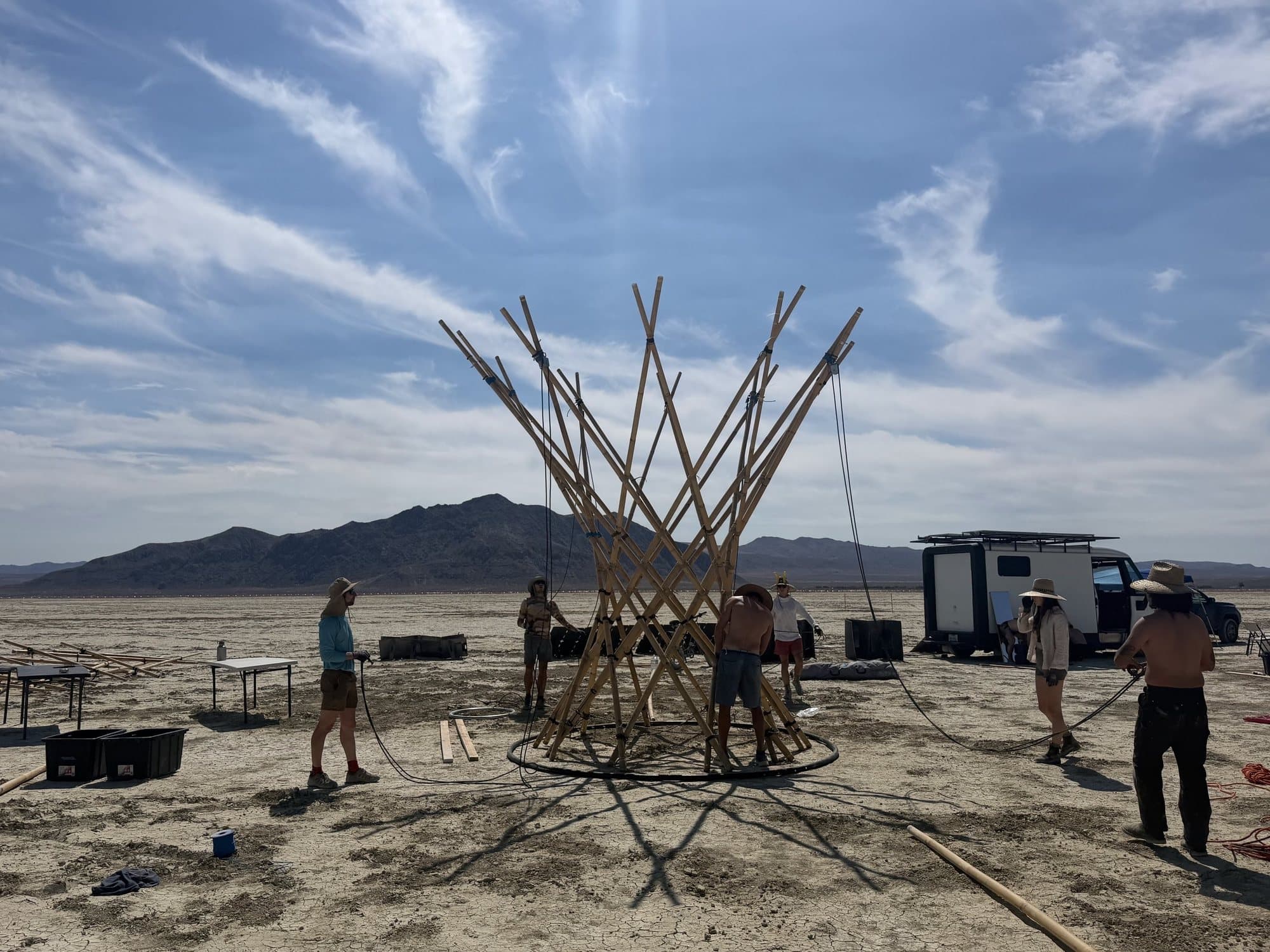 The Resonance Tree build on the playa: the raised bamboo trunk with the whole crew at work around its foot, the Black Rock range behind