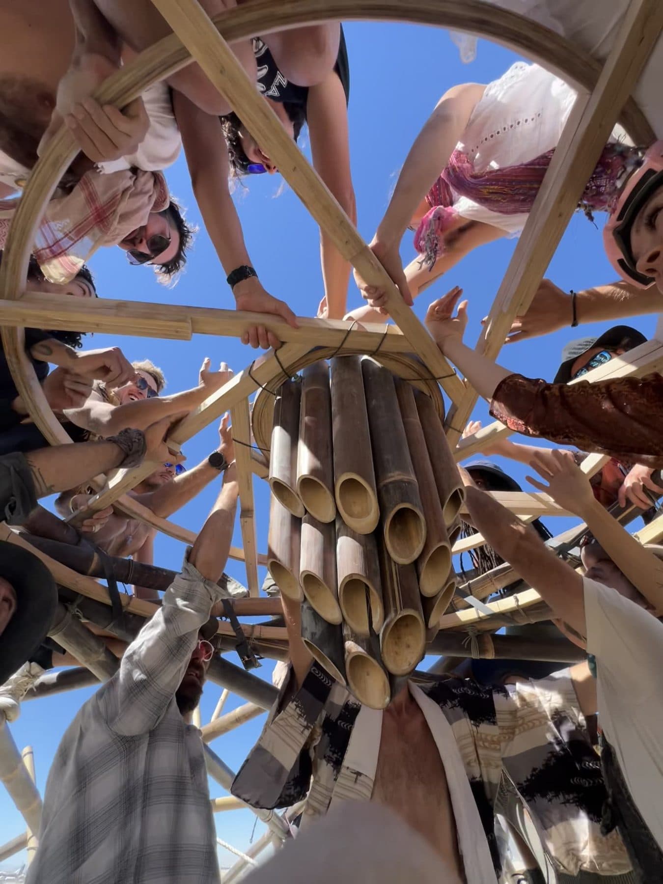 Many hands raised together around the central bamboo bundle in the crown