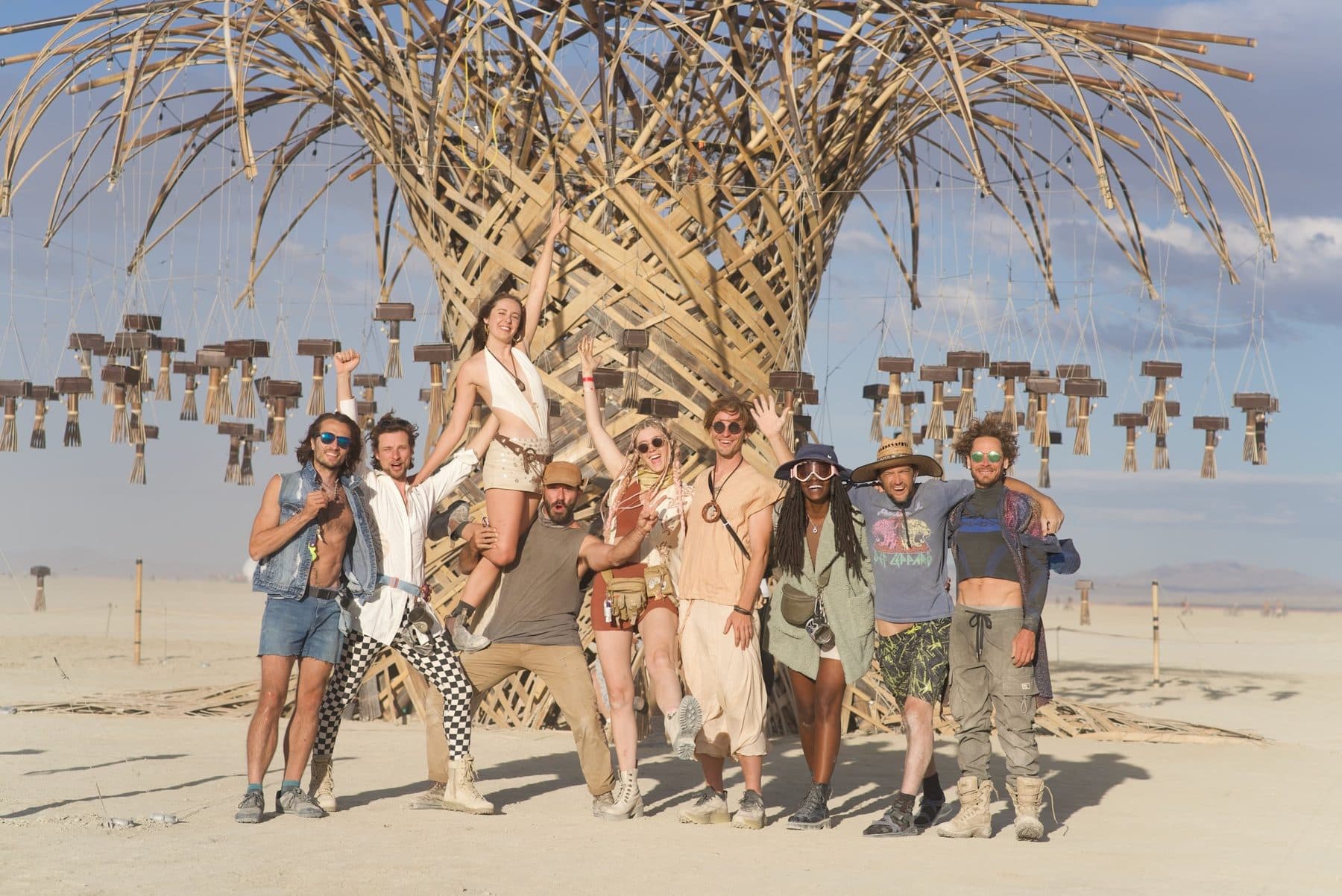 The crew at the foot of the Resonance Tree, arms up, one of them lifted high